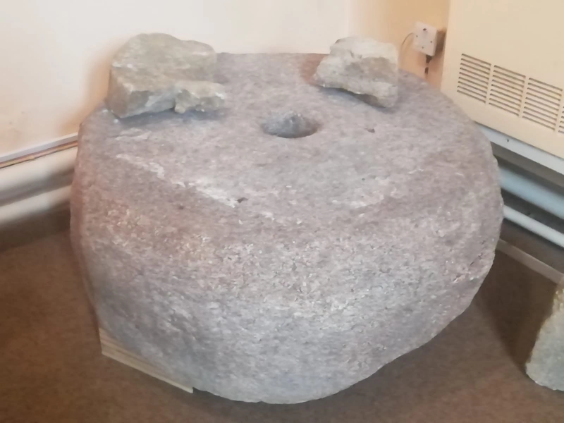 The lower millstone is of an early medieval horizontal water mill. It was used for grinding grain and was probably located on the nearby Santry river.  (Dr Colin Rynne). It is comprised of  pink granite which does not crop out as bedrock locally in Dublin. It’s origin may have been in the Mournes or west of Galway city as both of these areas have bedrock pink granite. (Dr Robert Meehan)